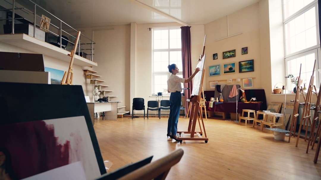 An artist works on a canvas in a bright studio.